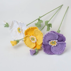 Detail of handmade crochet poppy flowers in white yellow and purple with knit leaves