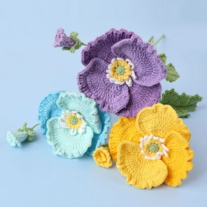 Handmade crochet poppy bouquet with purple, blue, and yellow flowers on blue background
