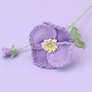 Detailed view of hand-knitted purple pansy flower with green stem and leaf
