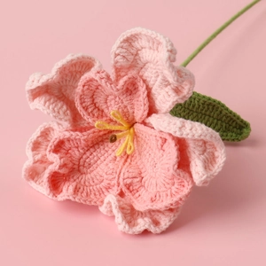 Detailed macro view of handmade crochet lisianthus with pink petals and green leaves