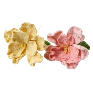 Handmade crochet flowers in pink and yellow with green leaves on white background