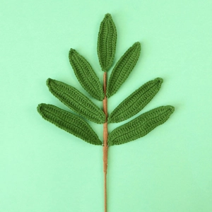 Detail of hand-knitted olive leaf branch with seven dark green crochet leaves and brown stem