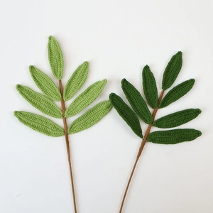 Detail of handmade crochet green leaves with intricate woven textures on brown stems