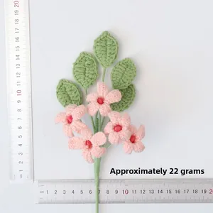 Detailed view of handmade crochet pink flowers and green leaves with measuring scale