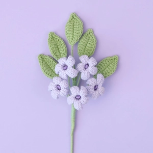 Detail of handmade crochet purple jasmine flowers with fine knit texture and green leaves