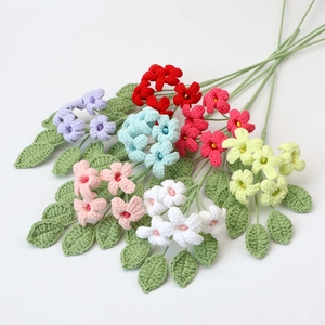 Handmade crochet colorful bouquet with assorted knitted flowers and green leaves on white background