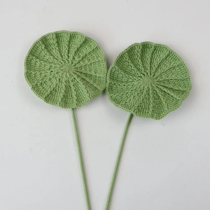 Detailed close-up of two handmade crochet green lotus leaves with spiral woven texture