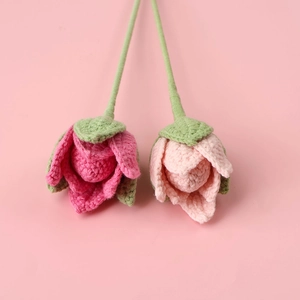 Detailed knit texture of handmade crochet pink rose buds with green stems for home decor