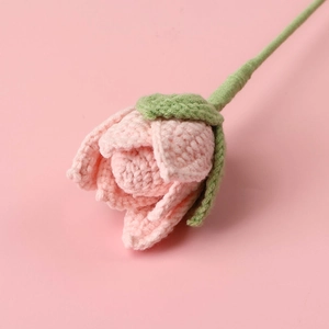 Macro shot of handmade crochet lotus bud with delicate pink petals and green stem
