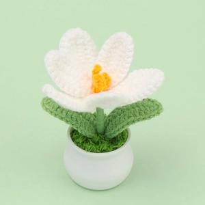 Detail of white crochet tulip in white ceramic pot with handmade knitting textures