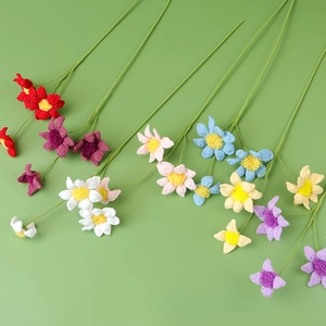 Close-up of handmade crochet daisies in vibrant colors with green stems for home decor