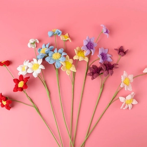 Colorful handmade crochet daisies on a pink background for home floral decoration