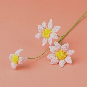 Detailed close-up of handmade crochet daisies with pink petals and yellow pompom centers