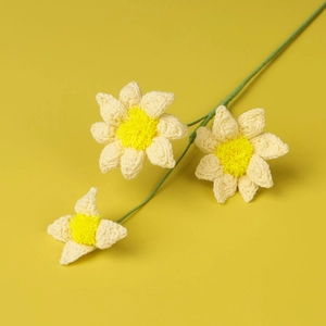 Detailed view of handmade crochet small yellow daisies with three flower heads on a stem