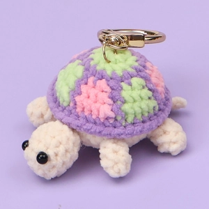 Close-up of handmade crochet turtle keychain with colorful shell and gold lobster clasp