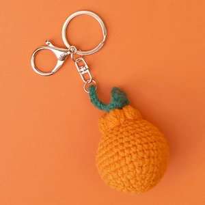 Close-up of handmade crochet orange keychain with leaf detail and silver lobster clasp