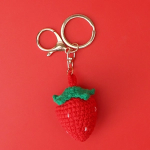 Detailed close-up of handmade crochet strawberry keychain with golden lobster clasp