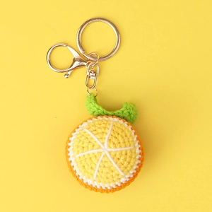 Close-up of handmade crochet orange fruit slice keychain with golden metal clasp