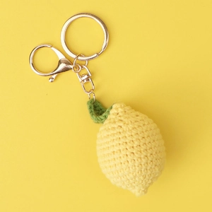 Macro view of handmade crochet lemon keychain with yellow yarn and green leaves