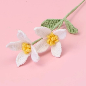 Detail of hand-crocheted white flowers with yellow centers and green knitted leaves