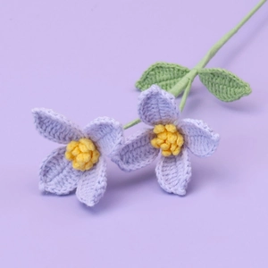 Close-up of handmade purple crochet flowers with yellow stamens and green leaves