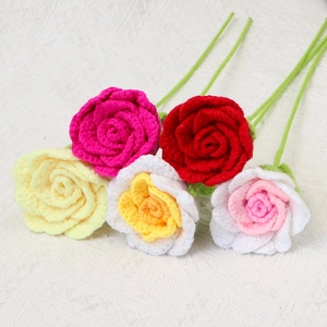 Detail view of five handcrafted crochet roses in assorted colors on white lace fabric