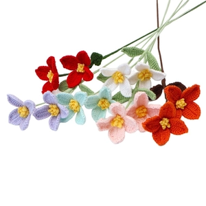 Handmade multicolored crochet flower bouquet with green leaves on white background