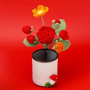 Detail of handmade crocheted red rose and strawberry bouquet in a black wire pen holder