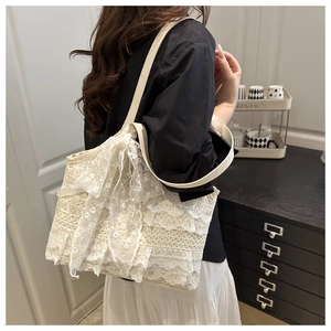 Detailed view of layered white lace tote bag with large bow and leather strap