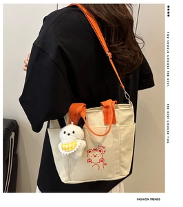 Rear view of a model wearing the cream canvas tote bag with orange straps and cute bear