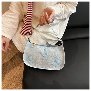 Détail du sac hobo bleu clair avec broderie papillon vintage et fermeture éclair dorée