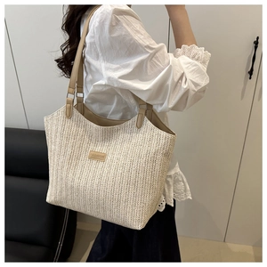 Detail of large woven straw tote bag with brown leather straps and fashion label