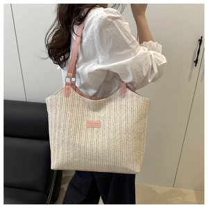 Detail of woven straw tote bag featuring pink leather strap and FASHION brand patch