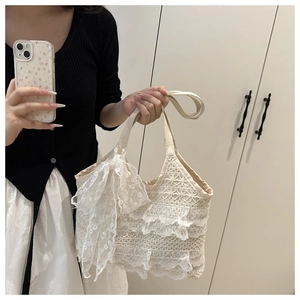 Detail of white tiered lace tote bag featuring a decorative oversized side bow design
