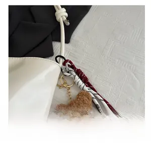 Close-up of a cute brown plush bear bag charm with a golden clasp and braided rope detail