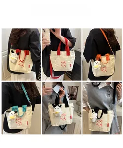 Detail of color-block canvas tote bag featuring bear print and plush puppy pendant
