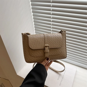Khaki woven texture small square crossbody bag with buckle closure on natural background