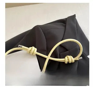 Detail of light yellow leather shoulder strap with elegant decorative knots and metal tips