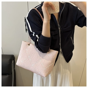 Close-up of pink floral embroidery texture and gold chain strap on shoulder bag