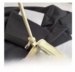 Detailed close-up of smooth metal zipper and matte leather finish on a cream pillow bag