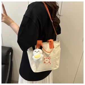 Close-up of contrast canvas tote bag with orange straps and cute bear print detail