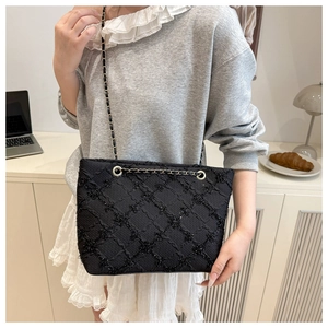 Detail of black quilted chain tote bag on a desk with a warm lifestyle setting