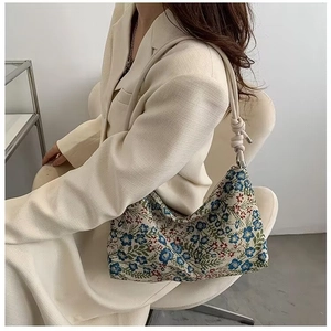 Detail of floral canvas underarm bag with knotted beige strap and ethnic pattern finish