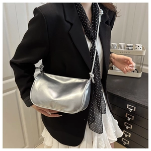 Detail van zilveren metallic crossbodytas met geknoopte riem en modebelettering