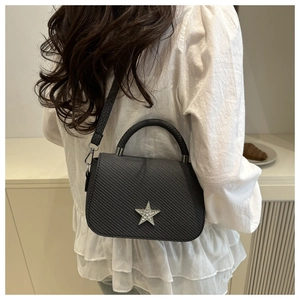 Detailaufnahme einer schwarzen Stepptasche mit silbernem Strassstern und Ledergriff