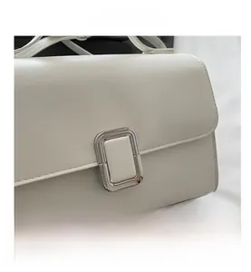 Gros plan d'une boucle rectangulaire en métal argenté sur un sac bandoulière blanc