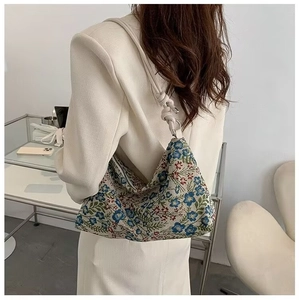 Detail of floral tapestry handbag showing intricate fabric texture and knotted shoulder strap