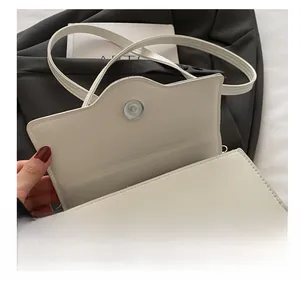 Detailaufnahme des silbernen Magnetverschlusses einer weißen Kunstleder-Handtasche