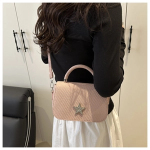 Dettaglio borsa a tracolla rosa con stella di cristallo e trama intrecciata su modella