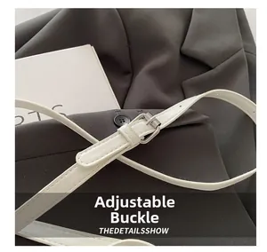 Détail de la boucle en métal argenté ajustable sur une bandoulière blanche